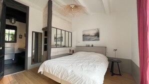 A bedroom with a large bed, a wooden floor, a mirror, a bedside table, and a painting on the wall. - ALIZE              . (Rivedoux-Plage)