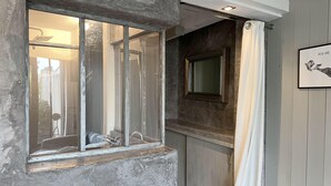 A bathroom with a bathtub, a shower, and a window with a view of the outside. - ALIZE              . (Rivedoux-Plage)