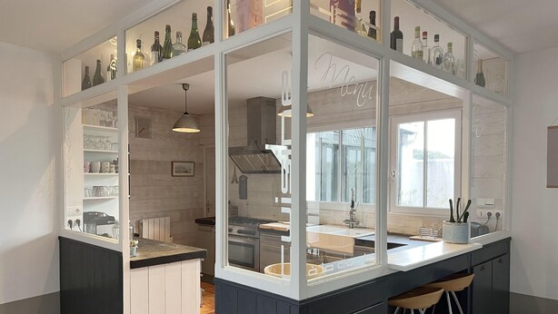 A modern kitchen with a central island, built-in shelves, and a view of the dining area. - ALIZE              . (Rivedoux-Plage)