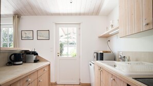Una cocina con armarios de madera, una encimera blanca, una cafetera, un microondas y un lavabo.