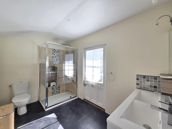 Een moderne badkamer met een douchecabine van glas, een toilet en een bad.