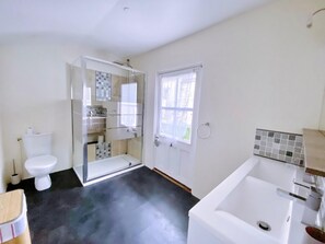 Bathroom features a white bathtub, glass-enclosed shower, and a toilet.