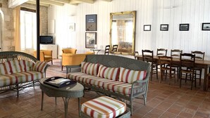 Una sala de estar acogedora con mobiliario de mimbre, una mesa de comedor con sillas y un televisor.