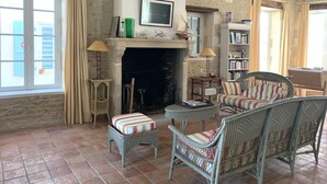 Una sala de estar acogedora con chimenea, muebles de mimbre y una estantería.