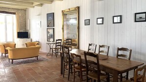 Un comedor con mesa y sillas de madera, televisor y cuadros en la pared.