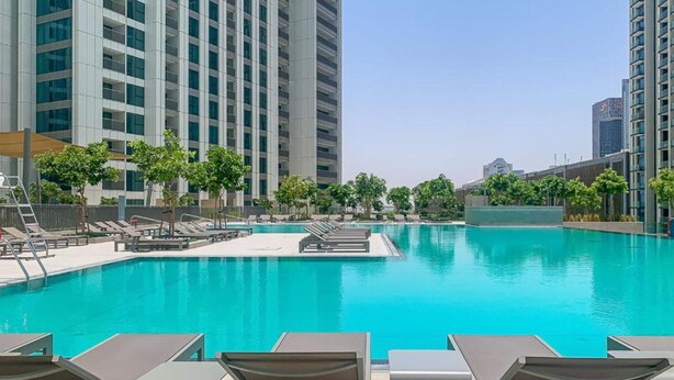 Una piscina con sillas de descanso y vistas a edificios altos.