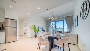 Una cocina moderna con un refrigerador de acero inoxidable, un comedor con una mesa redonda y sillas, y un ventanal con cortinas.