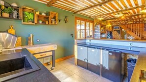 A kitchen with a wooden ceiling, a countertop with a sink, and a window.