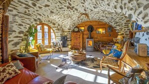 A cozy stone interior with a fireplace, wooden furniture, and a rustic ambiance.