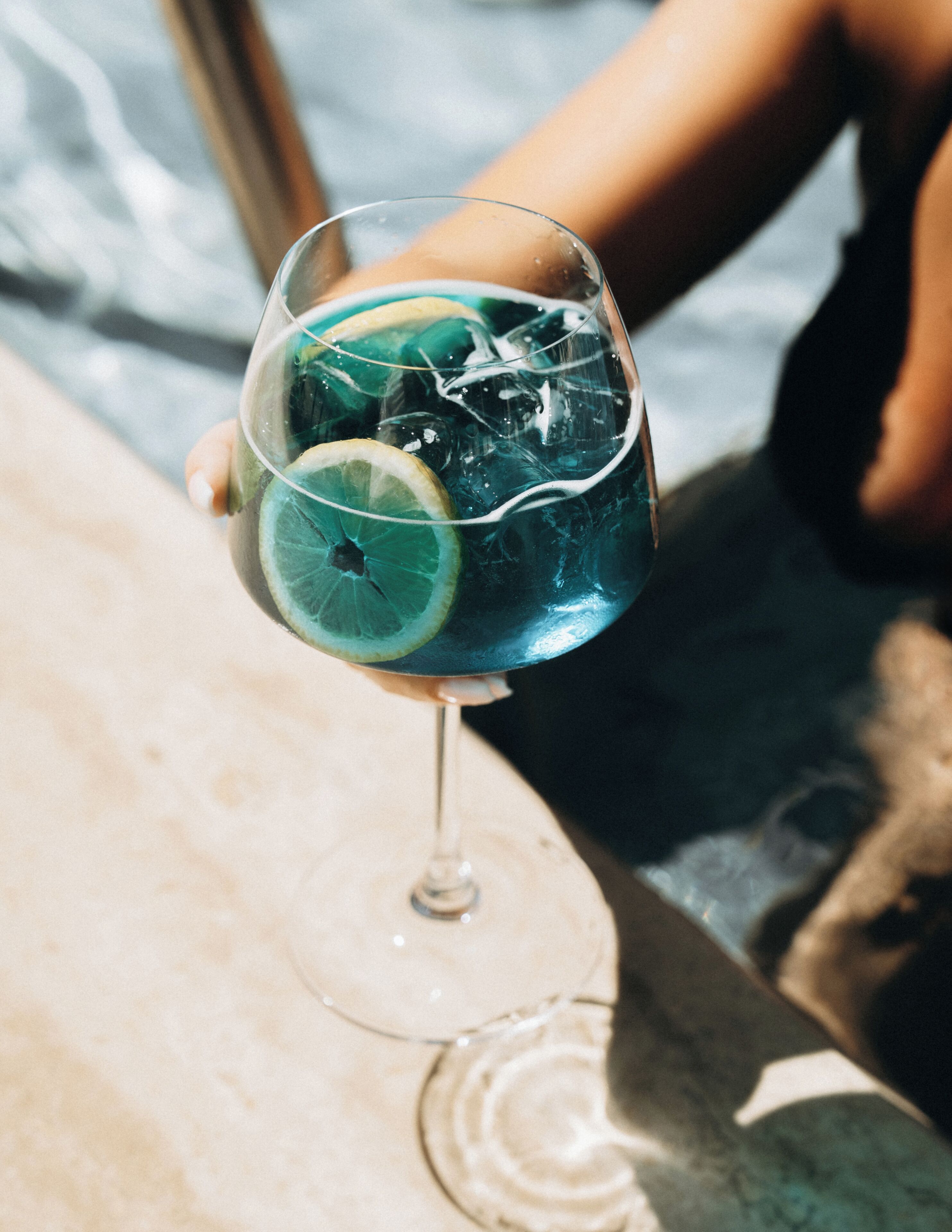 A glass with a blue liquid and a lime slice.