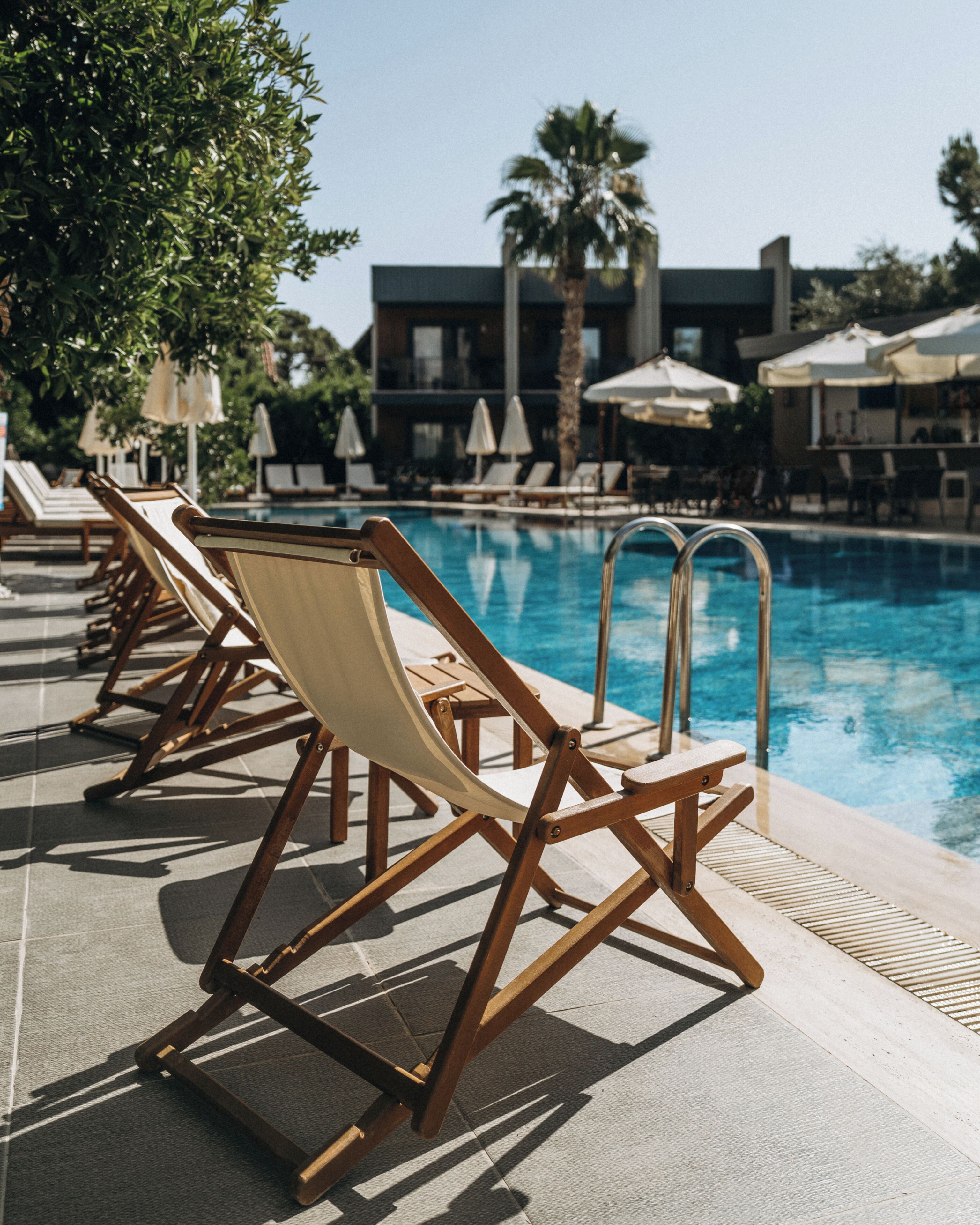 Un espace aménagé au bord de la piscine, avec des chaises longues, une piscine et un bâtiment en arrière-plan.