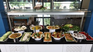 Un buffet con diversi piatti, tra cui insalate, carni e dolci, esposti su un bancone con vetrina.