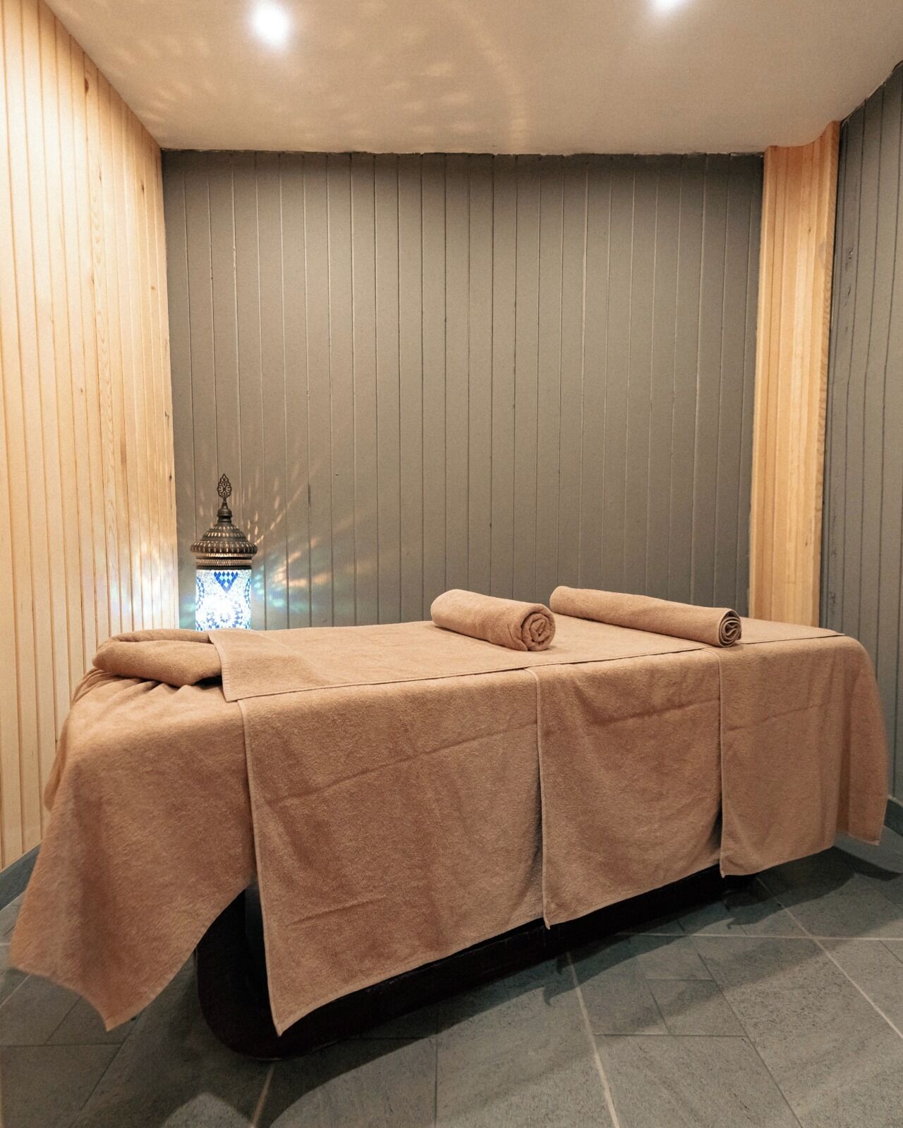 A massage table with towels, a small decorative item, and a wooden wall.