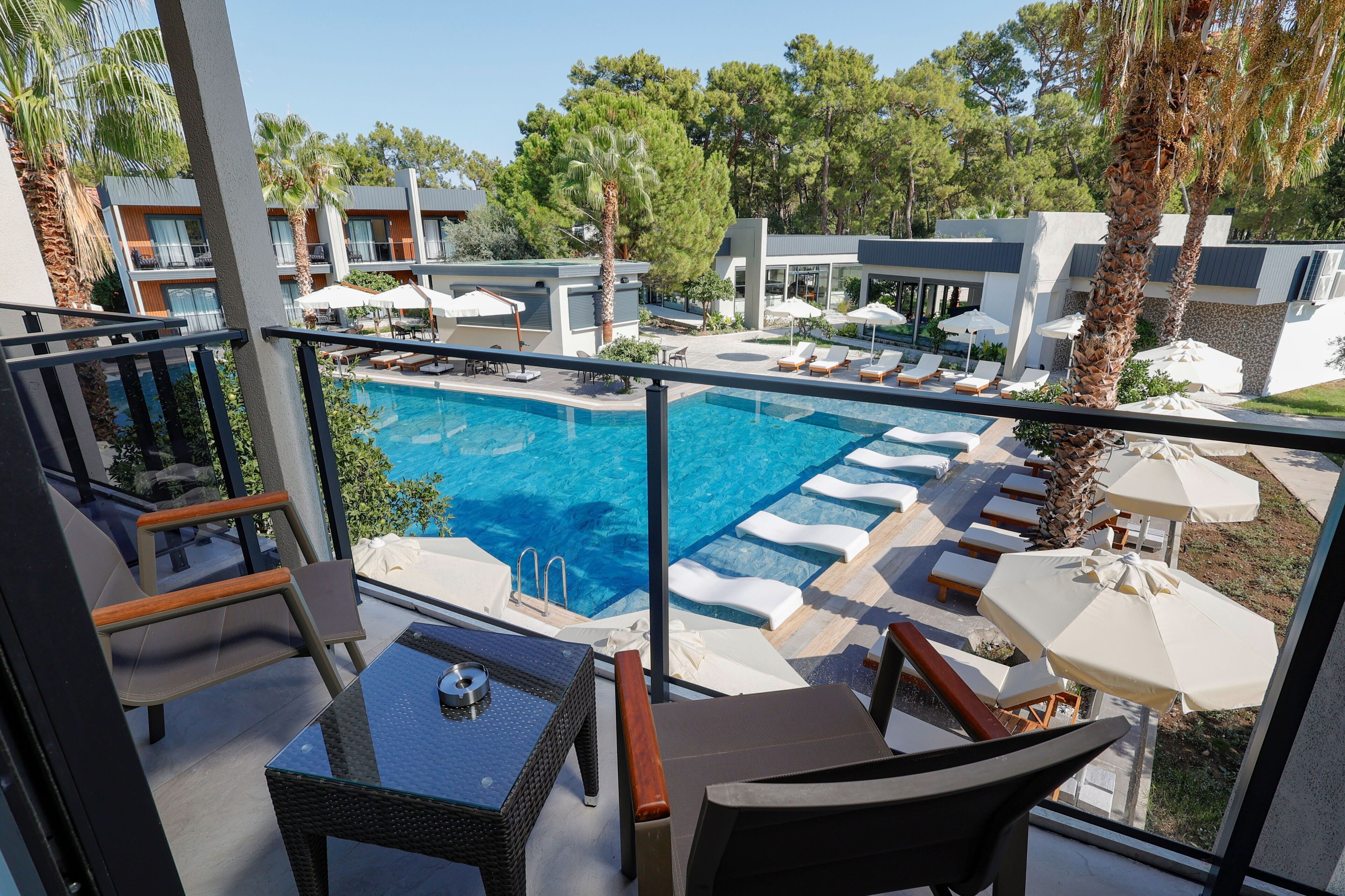 Zona de piscina con sillones de descanso, sombrillas y vista despejada al agua.