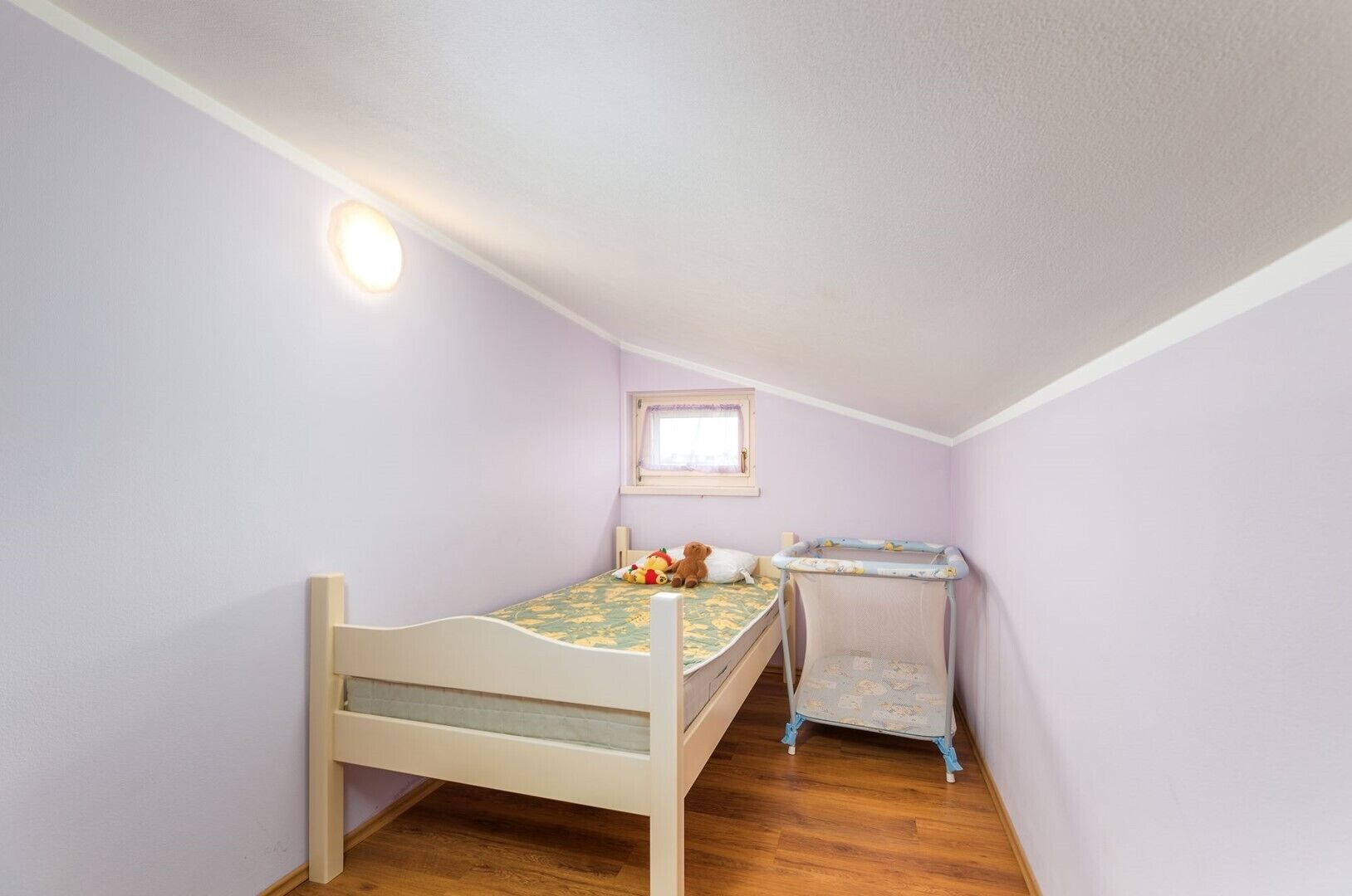 Una habitación pequeña con cama individual, una ventana, un escritorio pequeño y una silla.
