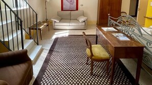 Amplia sala de estar con sofá, mesa de comedor y alfombra estampada.