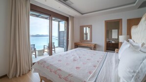 Habitación de hotel con una cama grande, un escritorio, una silla y vista al mar.