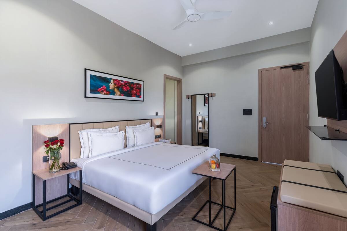 Ein modernes Hotelzimmer mit einem großen Bett, Nachttischen, einem Fernseher und einem Kleiderschrank.