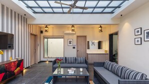 Een ruime woonkamer met een hoge plafond, glazen dak en een modern ontwerp.
