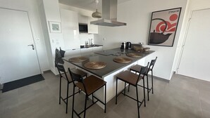 Eine moderne Küche mit Kochinsel, vier Stühlen und einer Pendelleuchte.