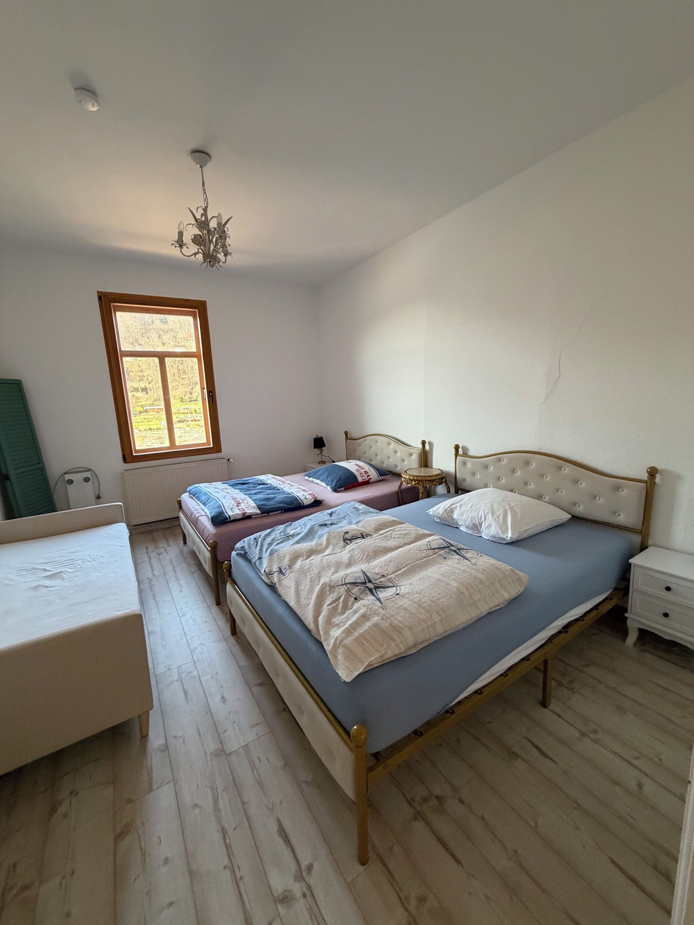 A bedroom with a bed, bedside table, lamp, window, and a chair.