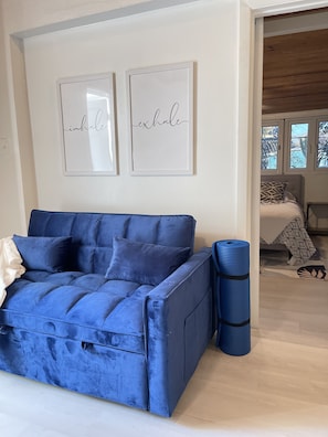 Ein blaues Sofa mit Kissen, ein blauer Mülleimer und zwei gerahmte Schilder an der Wand.