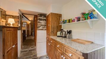 Una cocina con armarios de madera, encimera de granito y pared de piedra.