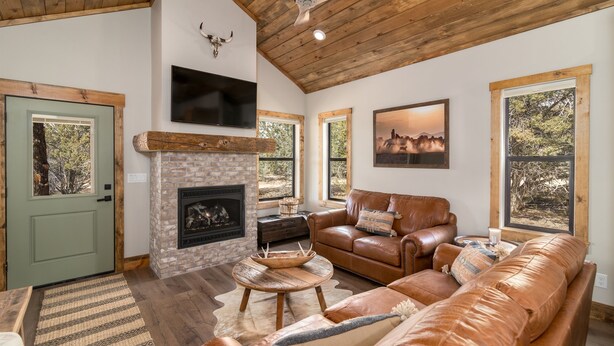 Un salón acogedor con chimenea, sofá de cuero y ventanas amplias.