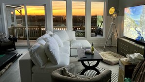 Ein modernes Wohnzimmer mit einem weißen Sofa, einem Couchtisch und einem großen Fernsehbildschirm.