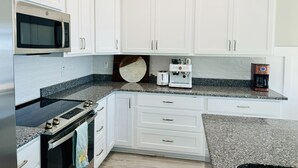 Eine moderne Küche mit weißen Schränken, einem Edelstahlbackofen, einer Mikrowelle, einer Kaffeemaschine und einem Toaster.