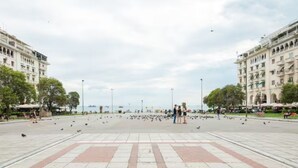 A spacious public square with a central open area, surrounded by buildings with balconies and trees. - Sleep in Style, Wake up in the Center of it All! (Thessaloniki)