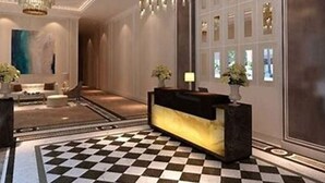 A lobby with a checkered floor, a reception desk, and a chandelier. - Saint Honore Condo (Iloilo)