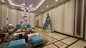A spacious lobby with a large Christmas tree, plush seating, and a chandelier. - Saint Honore Condo (Iloilo)