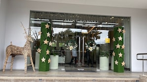 A hotel entrance with a glass door, a decorative star garland, and a wicker deer sculpture. - Saint Honore Condo (Iloilo)