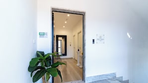 A hallway with a potted plant, a doormat, and a marble staircase. - Boutique B&B in Pompeii - Stay & Local Experiences (Pompei)