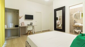 A hotel room with a bed, a desk, a TV, a wardrobe, and a bathroom with a mirror and sink. - Boutique B&B in Pompeii - Stay & Local Experiences (Pompei)