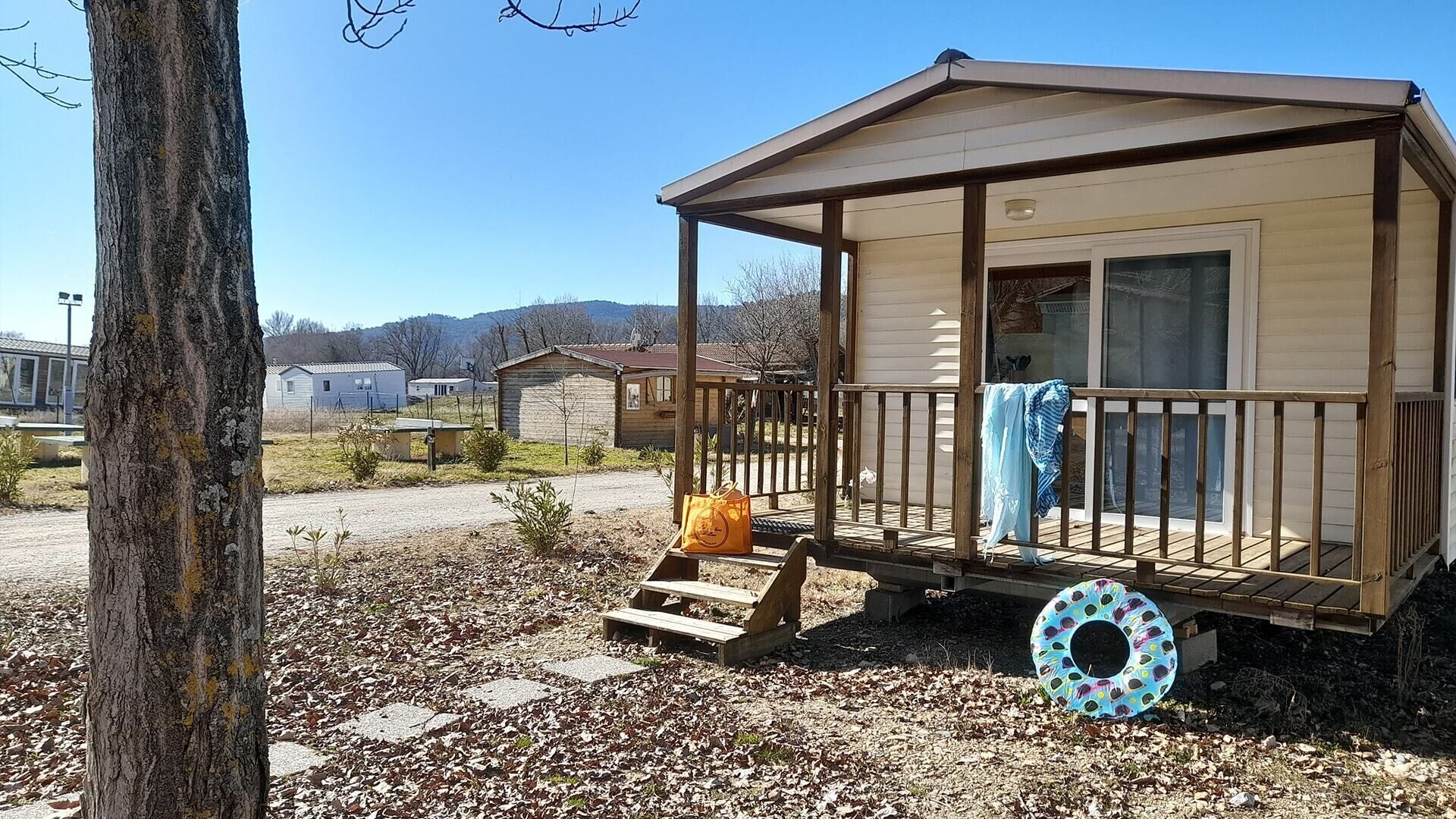 Una piccola baita di legno con un portico, una finestra e una porta.