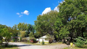 A campground with tents, a gravel path, and surrounding trees. - Camping la Célestine (Beynes)
