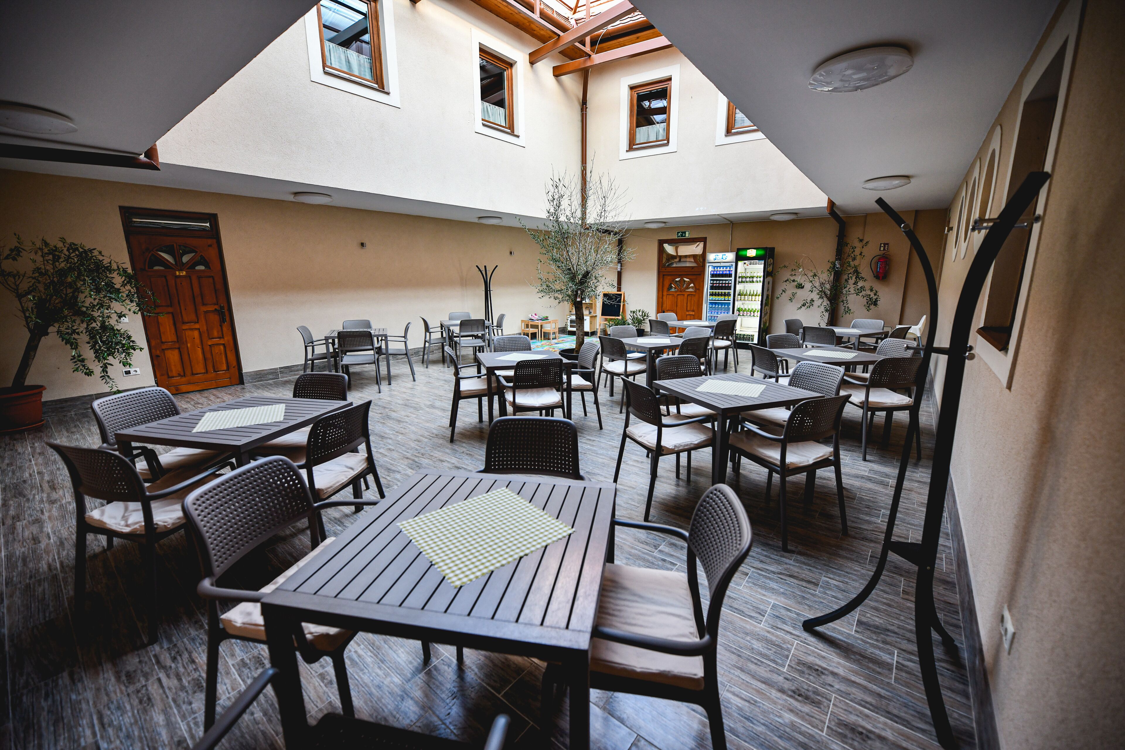 An indoor courtyard with multiple tables and chairs, a wooden door, and a vending machine.