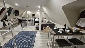 A modern loft-style apartment with a dining area, kitchenette, and a staircase leading to a lofted bedroom. - Végvári Hotel Eger (Eger)