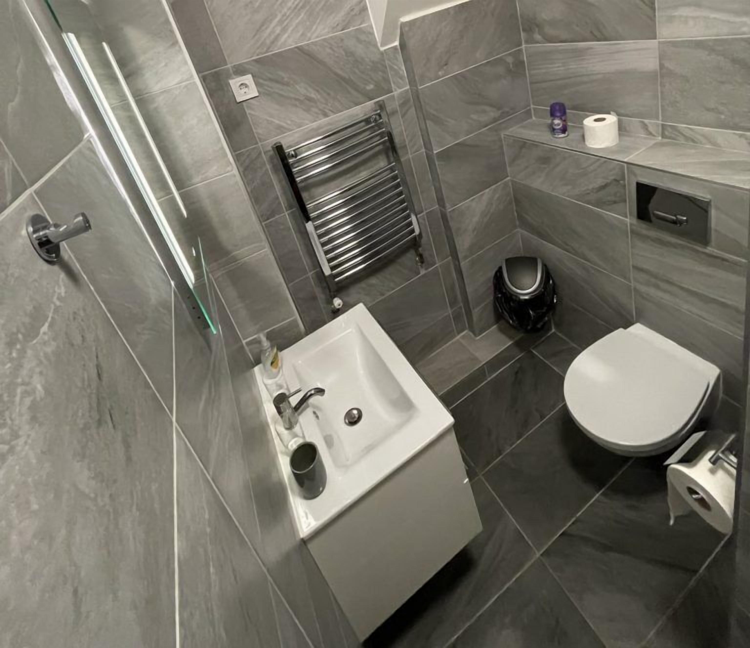 Een moderne badkamer met een wit wastafel, toilet en douche.