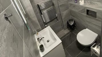 Een moderne badkamer met een wit wastafel, toilet en douche.