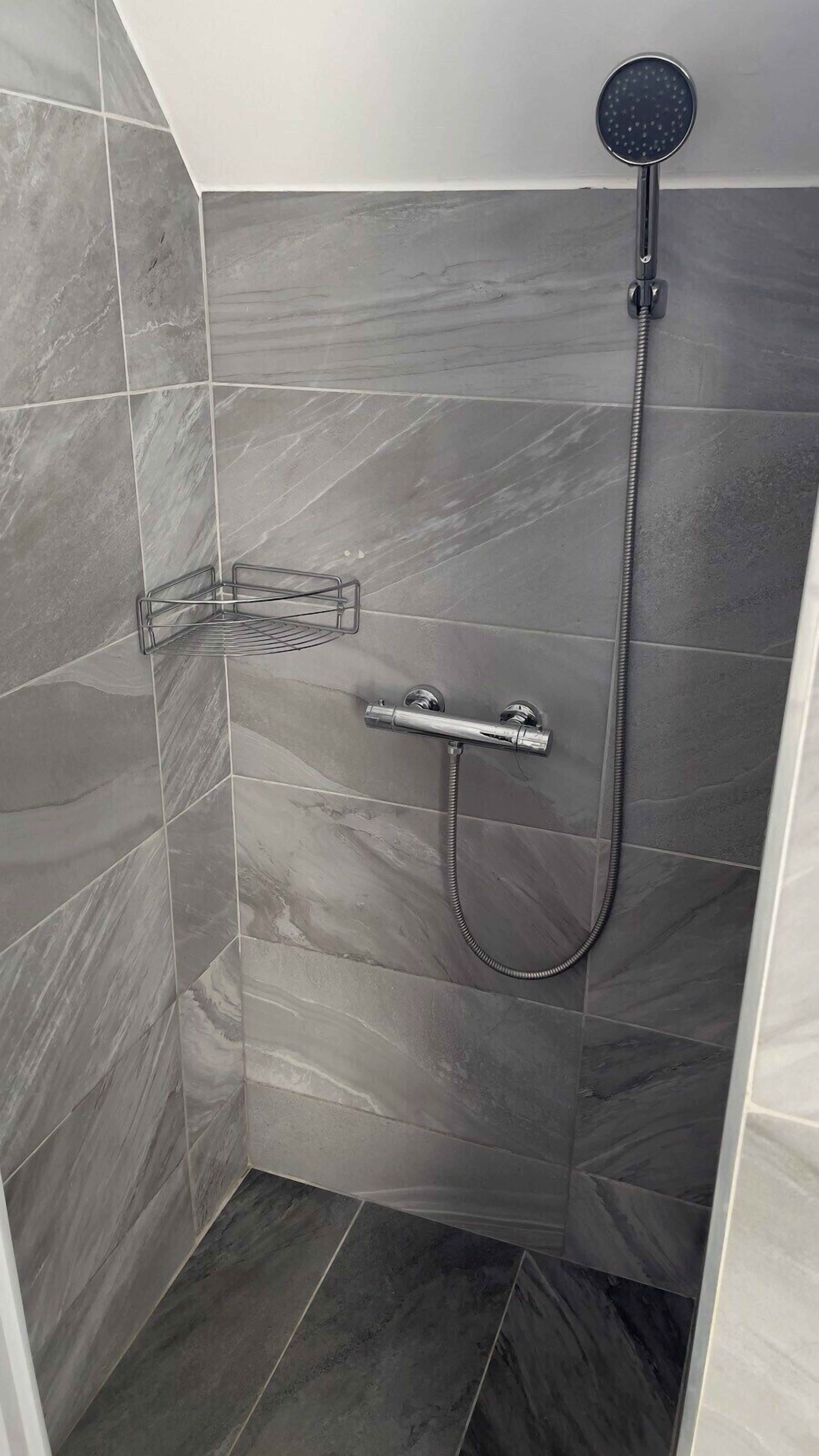 A shower with a handheld showerhead and a handheld hose.