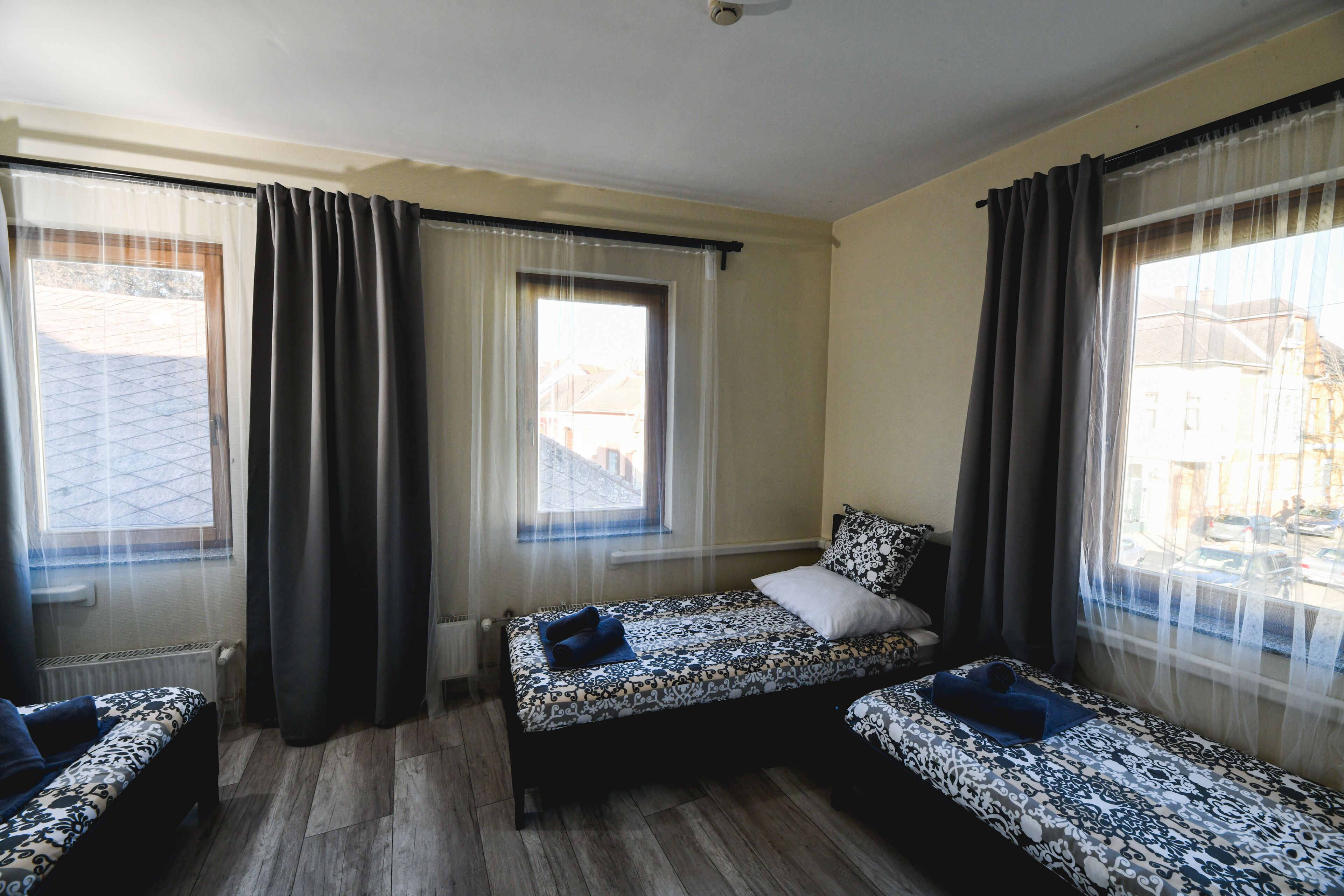 Une chambre avec deux lits, une fenêtre avec des rideaux et un radiateur.