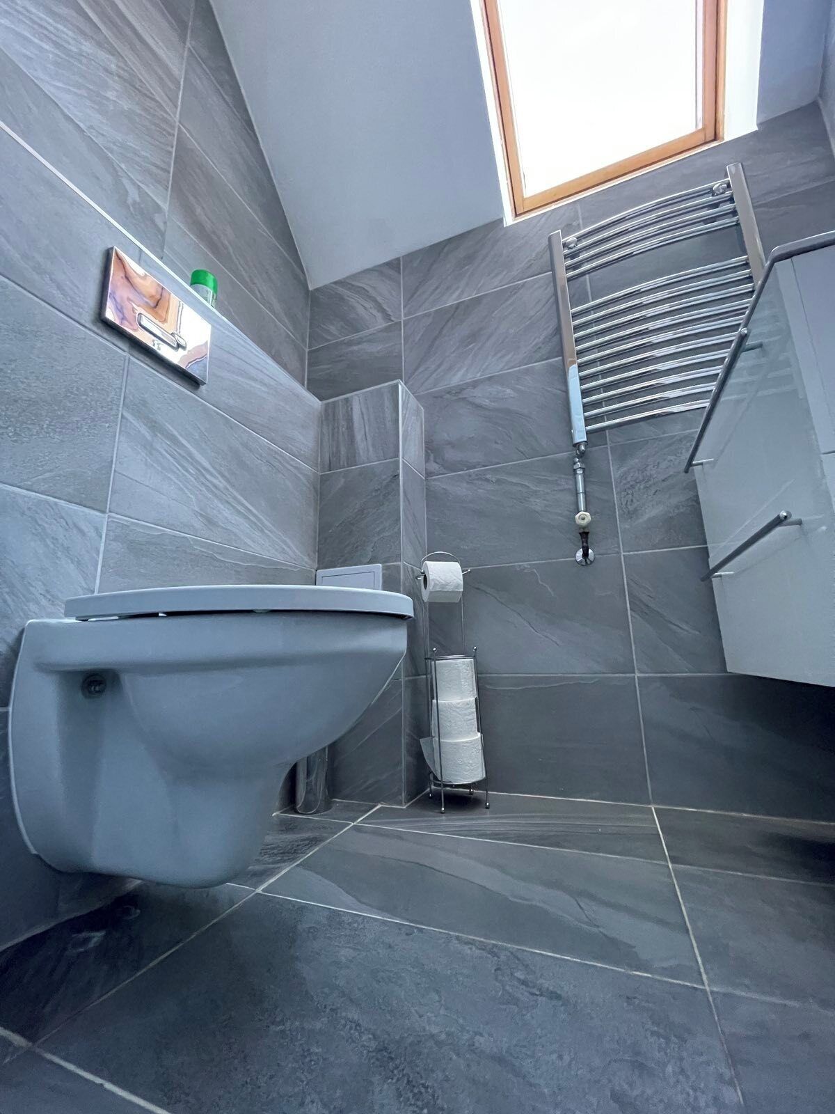 Une salle de bain moderne avec des toilettes, un porte-serviettes et une fenêtre.