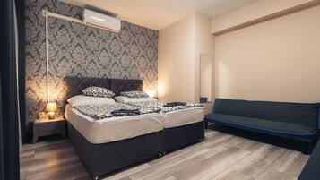 Quarto com cama, mesa de cabeceira, luminária, aparelho de ar condicionado e um sofá.