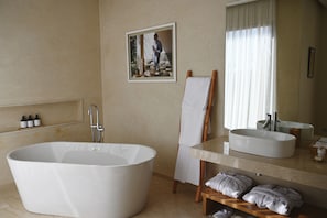 A modern bathroom with a freestanding bathtub, a large mirror, and a vanity with a sink. - Maison Kenoosha (Marrakech)