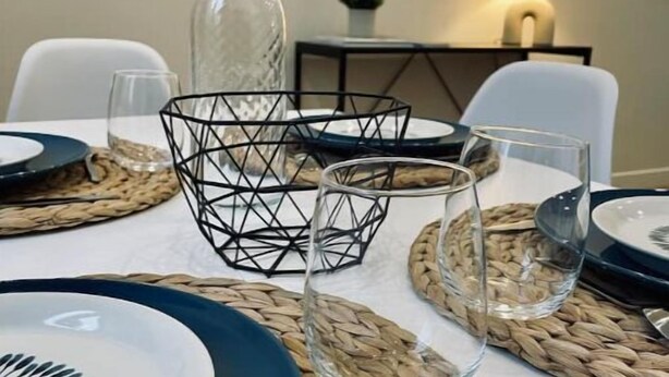 A dining table set with clear glassware, woven placemats, and a geometric black centerpiece. - Maison Amienoise Élégante (Amiens)