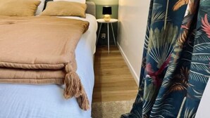 A bedroom with a bed, pillows, a nightstand, and a lamp. - Maison Amienoise Élégante (Amiens)