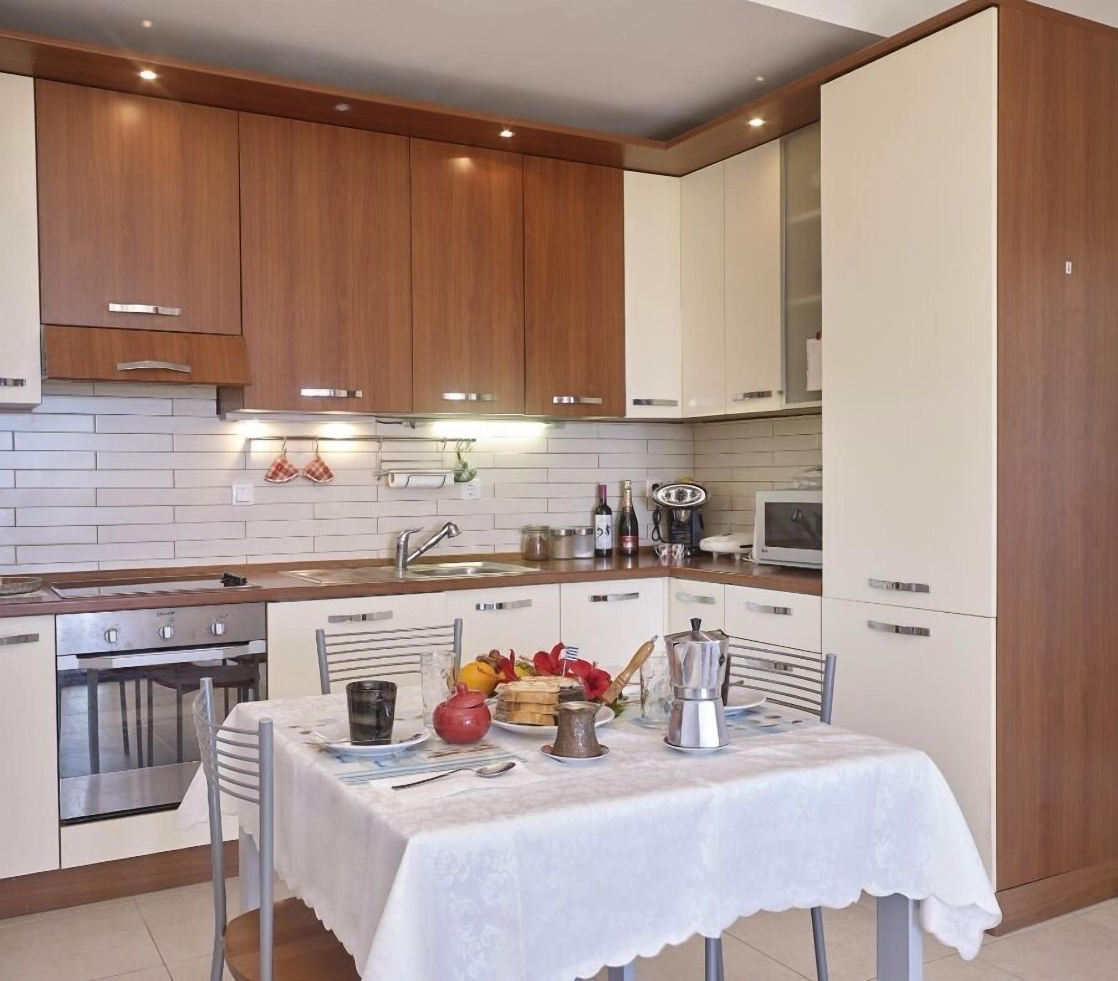 A modern kitchen with wooden cabinets, a stainless steel oven, and a dining area with a table set for two.
